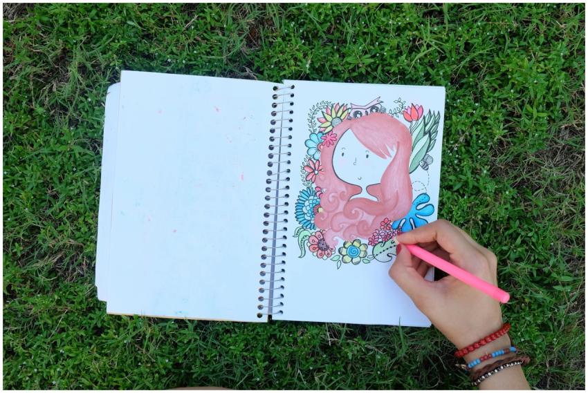 A hand drawing vibrant art in a sketchbook placed