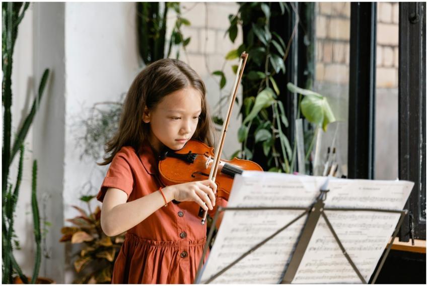 A young girl plays the violin with sheet music, fo