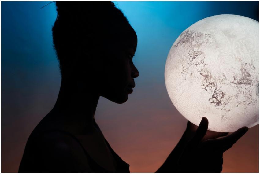Artistic silhouette of woman holding a glowing moo