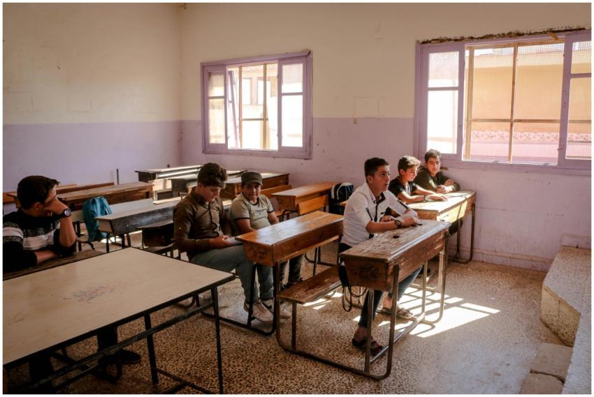 Teenagers sit attentively in a sunlit classroom in