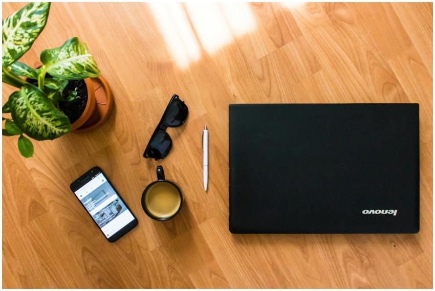 A flat lay of a desk with a laptop, coffee cup, sm