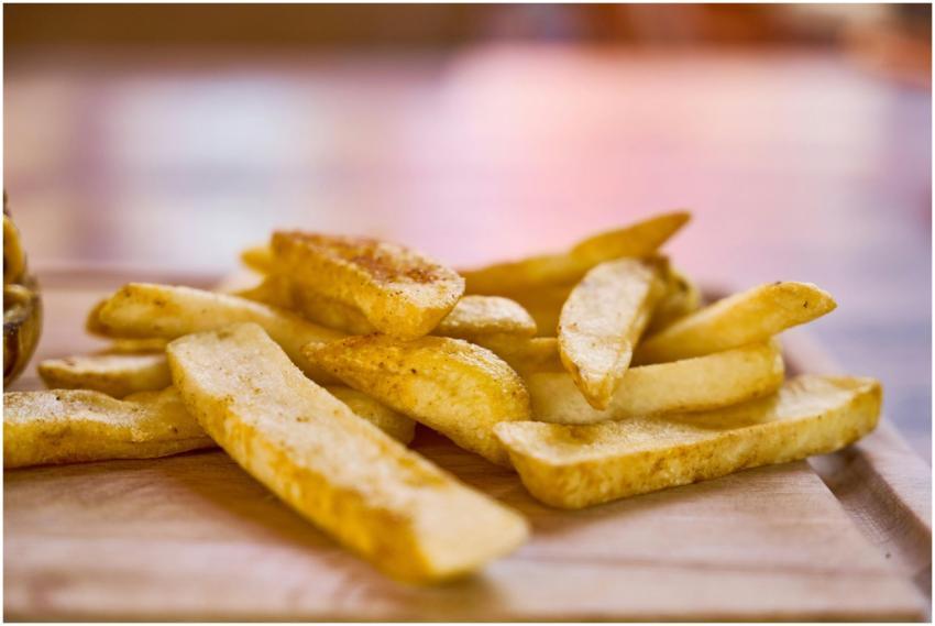 Crispy golden french fries on a wooden surface, re