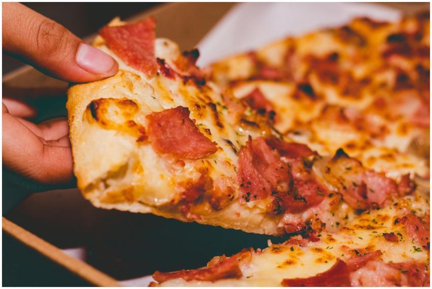 Close-up of a hand holding a delicious slice of pe