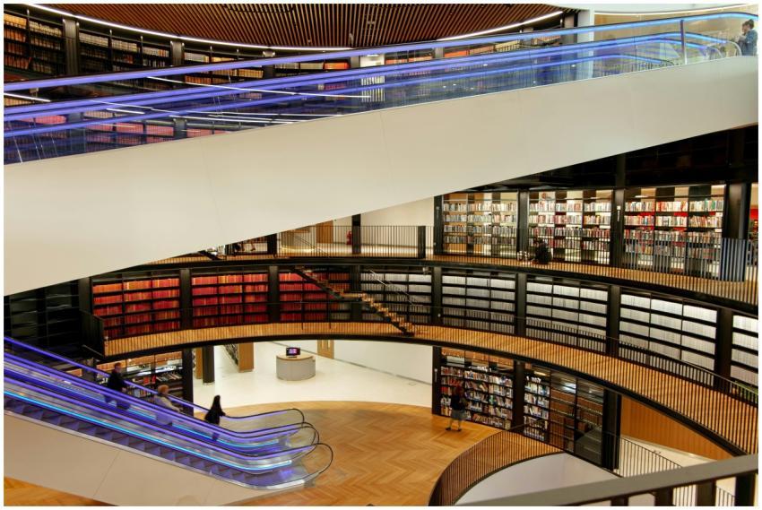 A spacious library with bookshelves, escalators, a