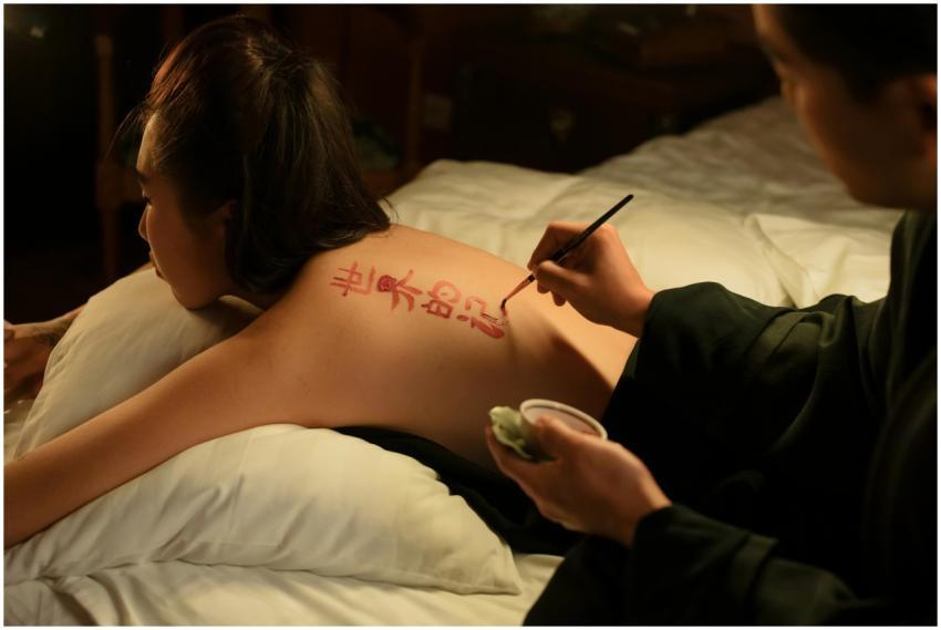 Asian artist paints intricate calligraphy on a wom