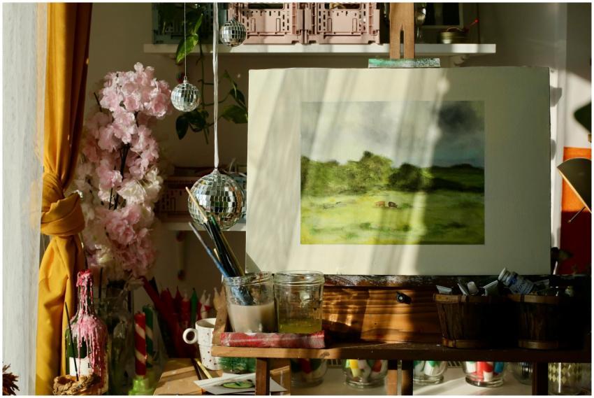 Sunlit art studio with painting supplies, easel, a