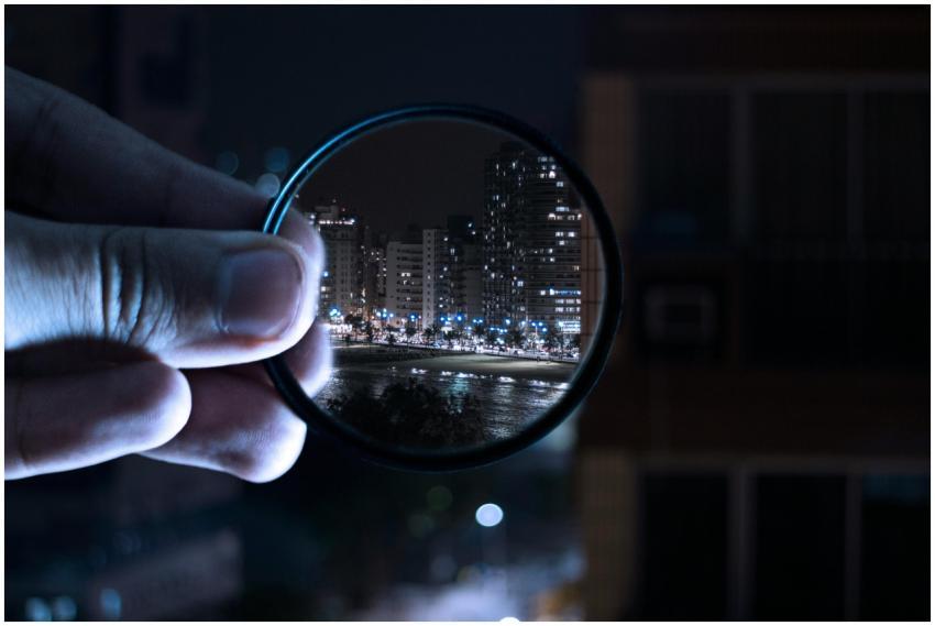 A hand holding a lens filter enhances a vibrant ci