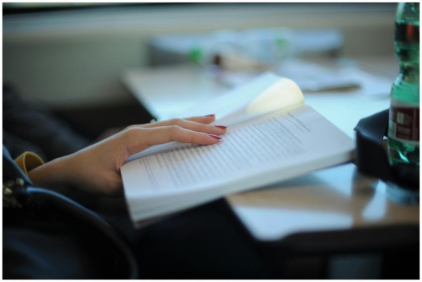 A woman with manicured nails is reading a book at