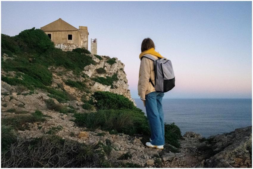 A backpacker gazes at an abandoned house perched o