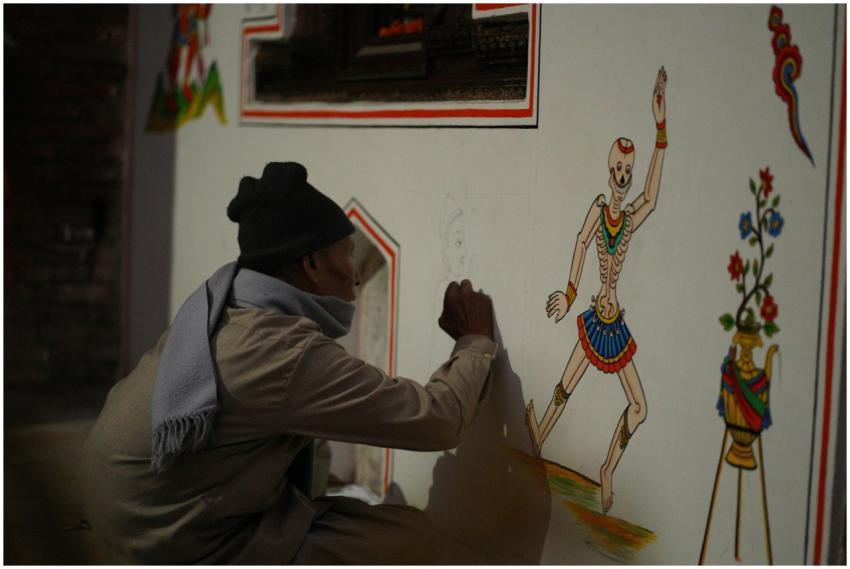 An artist creates a traditional mural on a temple