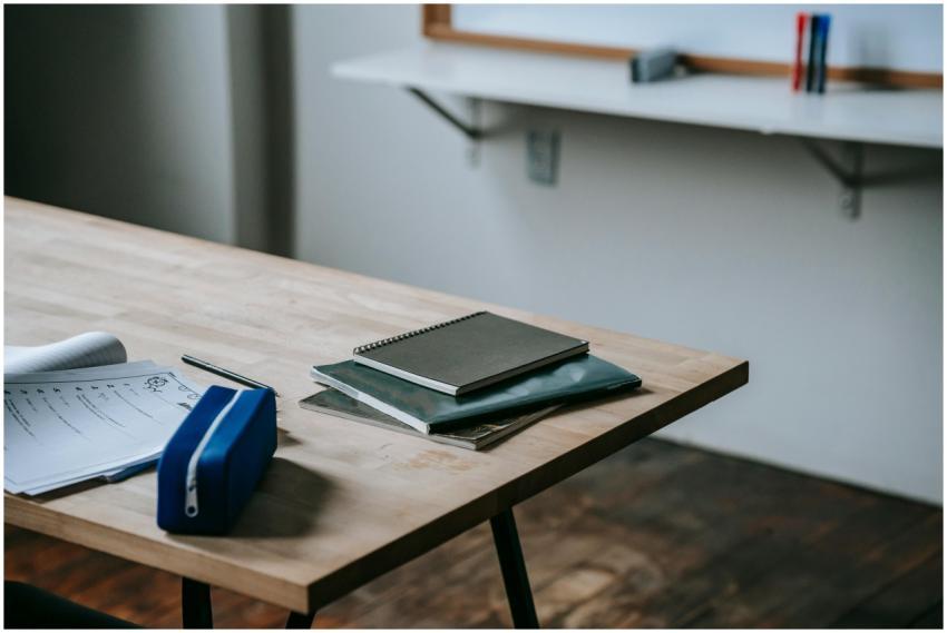 A neatly organized classroom desk with notebooks,