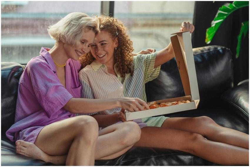 Joyful couple sitting on the couch sharing a pizza