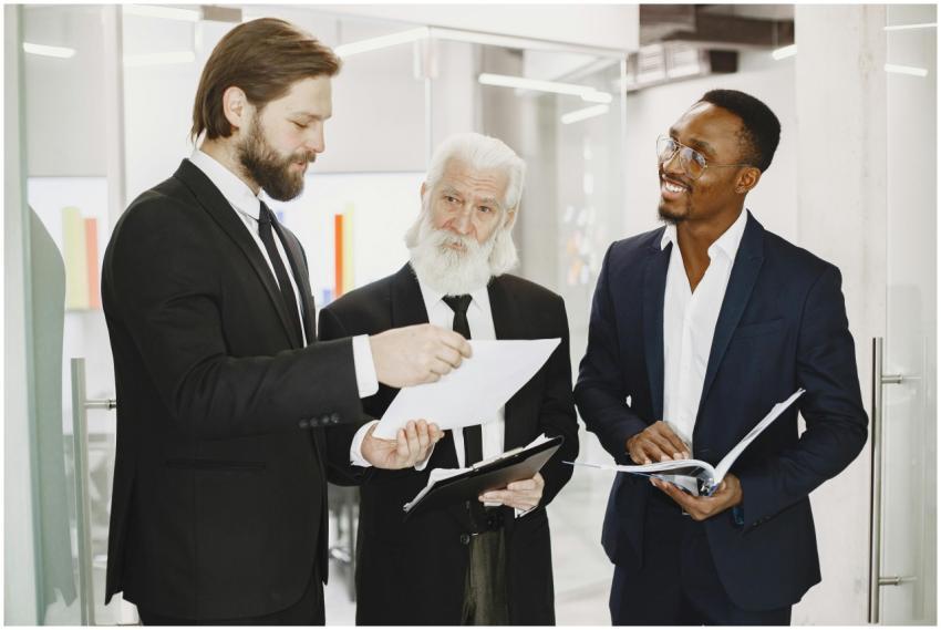 Three businessmen in suits discussing documents in
