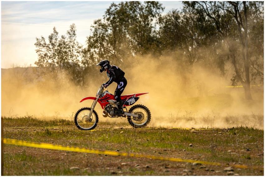 Motocross rider speeding through a dusty off-road