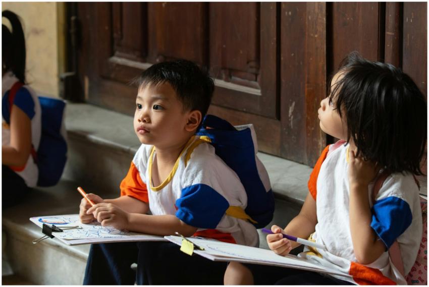 Children sitting with drawing materials indoors, f