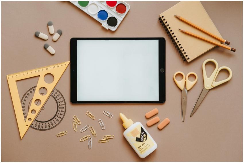 Flat lay of school supplies including tablet, scis
