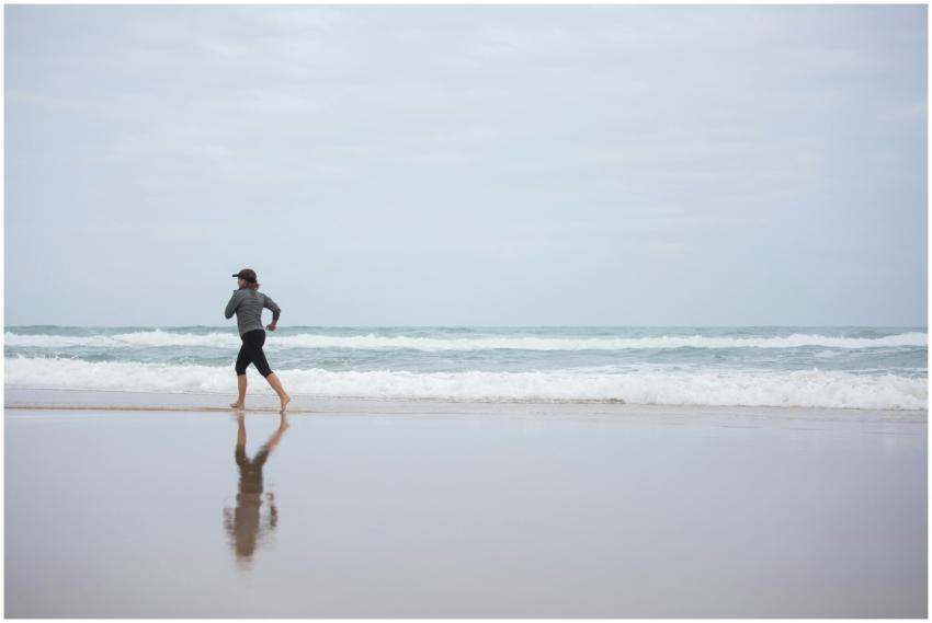 A woman runs on a serene beach, reflecting fitness