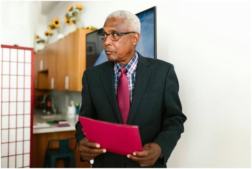 Senior businessman in suit holding a red folder, s