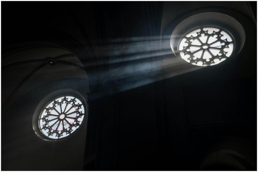 Sun rays illuminate ornate church rose windows, cr