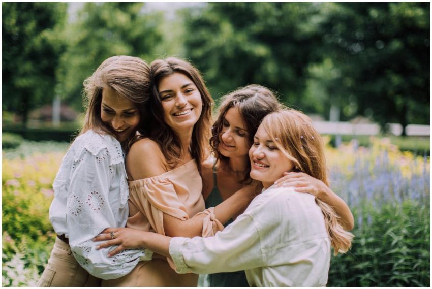 Four women joyfully embracing in a vibrant summer