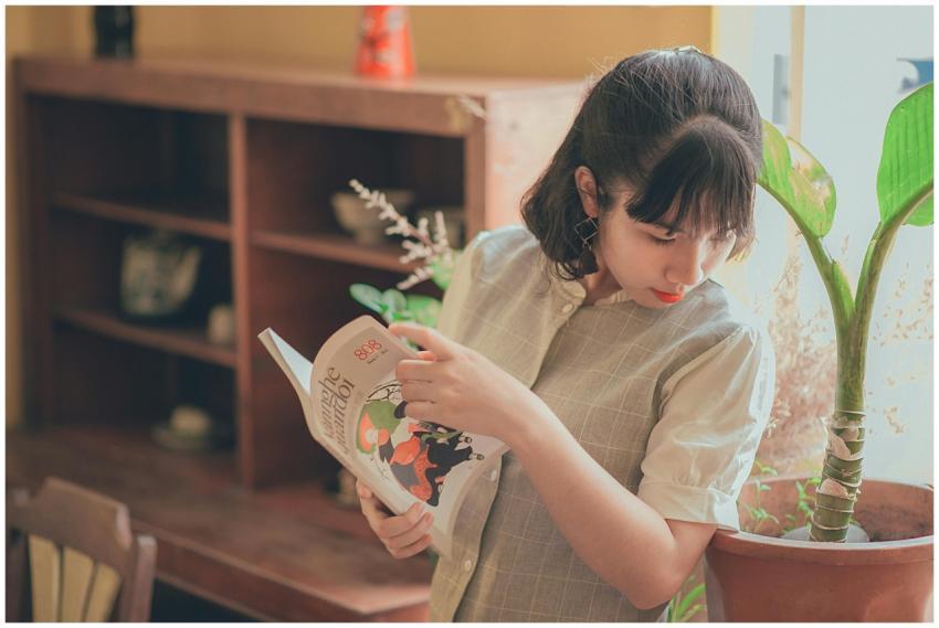 A young woman enjoying leisure reading near a sunl
