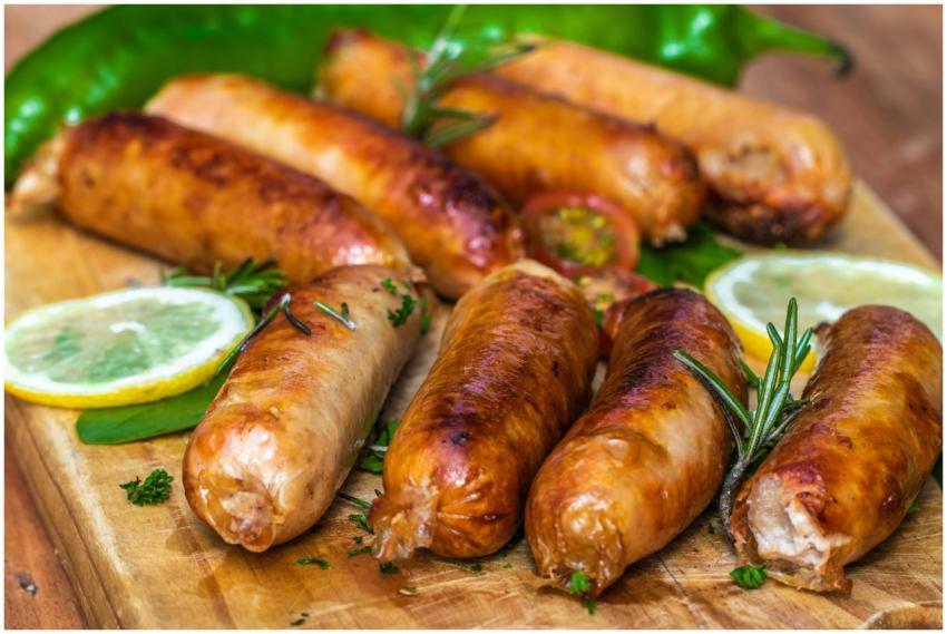 Juicy grilled sausages on a wooden board with lemo