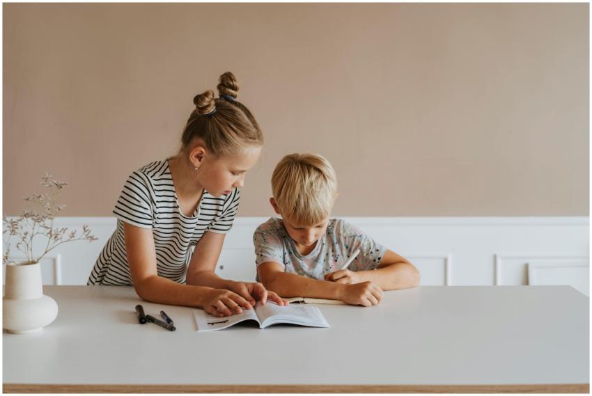 Two children studying together at home with books,