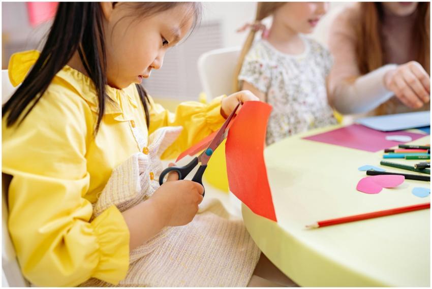 A young girl cuts colorful paper during an arts an