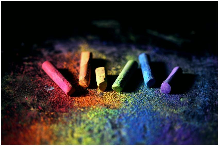 Colorful rainbow chalk pieces on dark background w