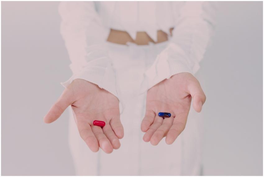 Close-up of hands holding red and blue pills, symb