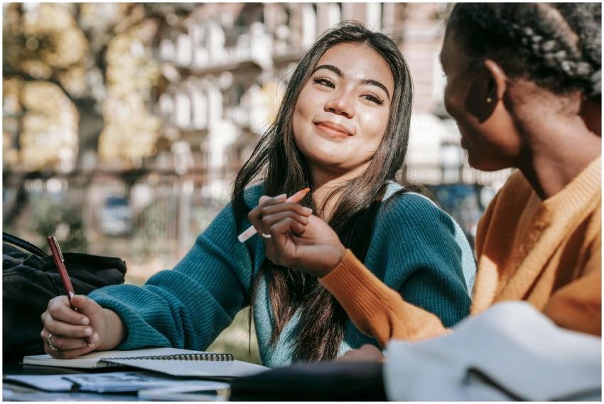 Two diverse female students studying together outs