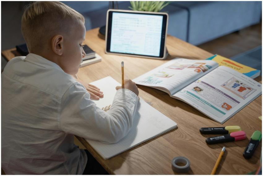 Young boy studying with notebook, pencil, and tabl