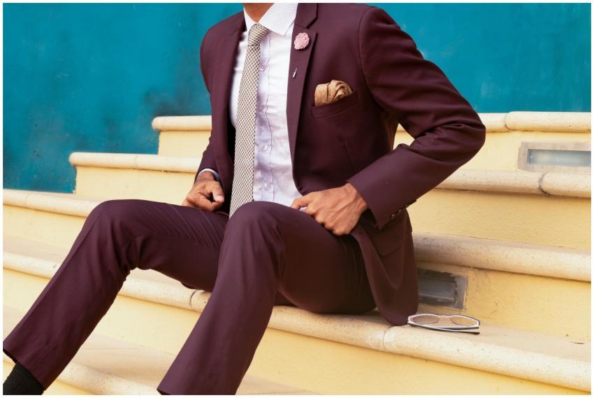 Elegant man in a burgundy suit sitting on steps, e