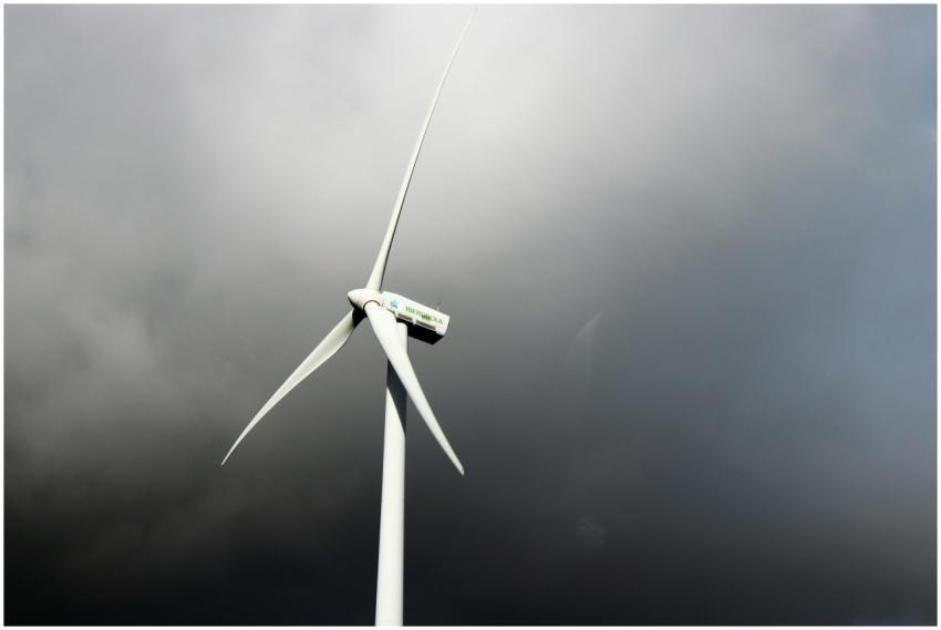 A wind turbine stands tall against a backdrop of d