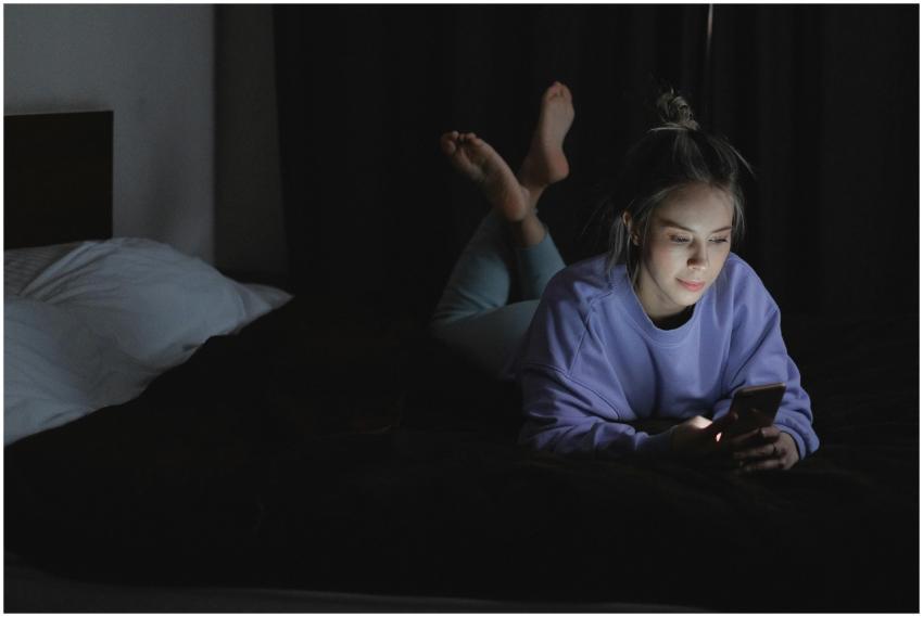 A woman lies in bed at night, using her smartphone