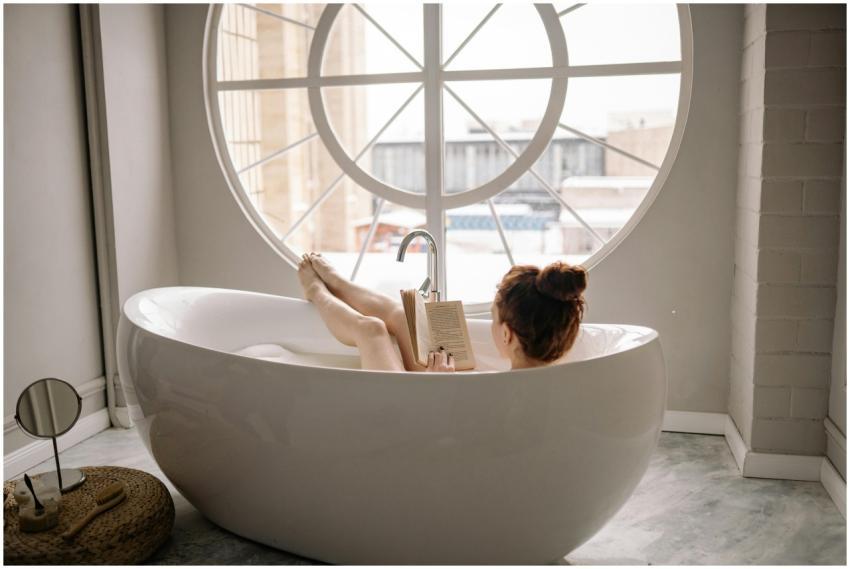 Woman enjoying a relaxing bath while reading a boo