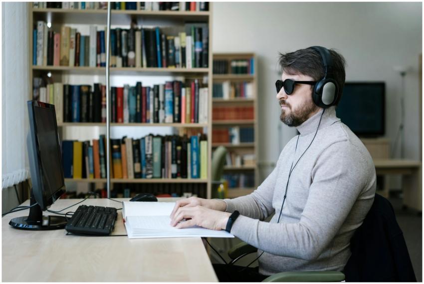 Blind man wearing headphones, working on braille b