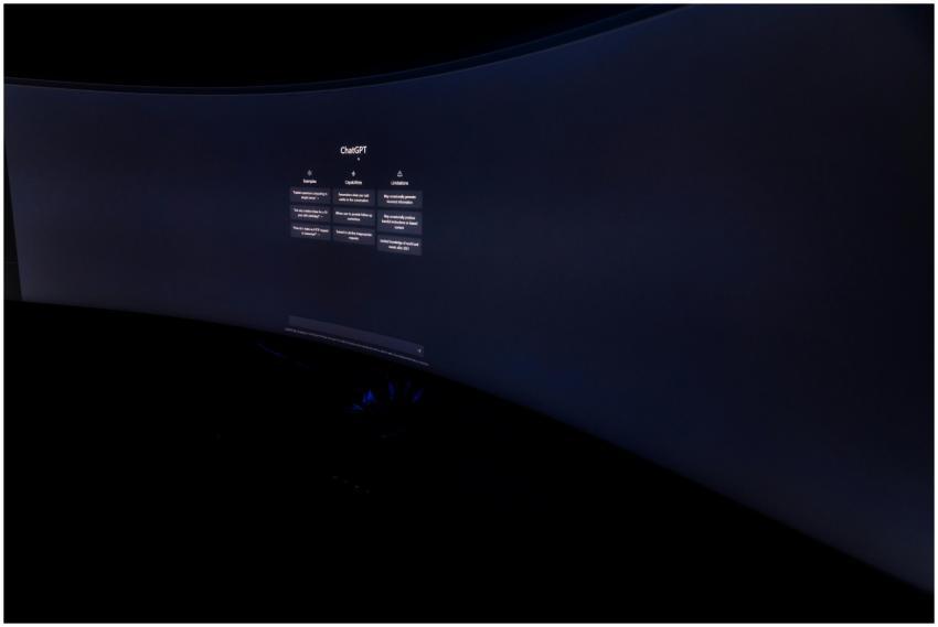 Curved monitor screen showing ChatGPT interface in