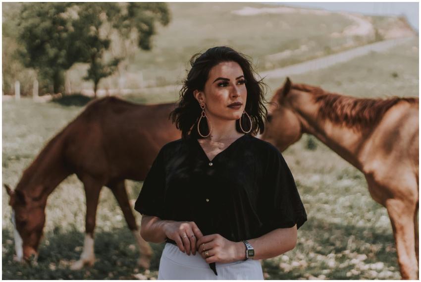 Portrait of a woman standing in a field with horse
