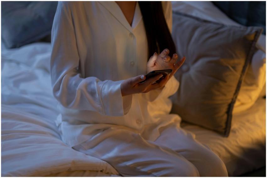 A woman in white pajamas using a smartphone while