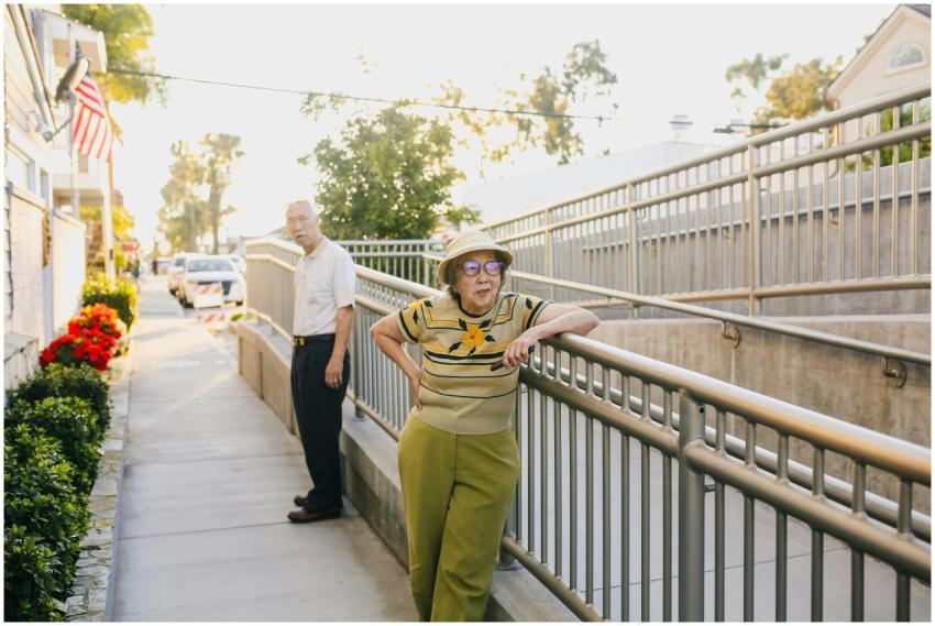 Elderly Asian couple relaxing outside near a raili