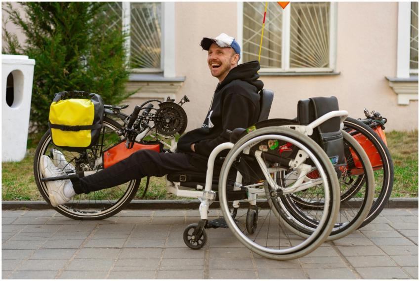 A smiling man sitting in a wheelchair next to an a