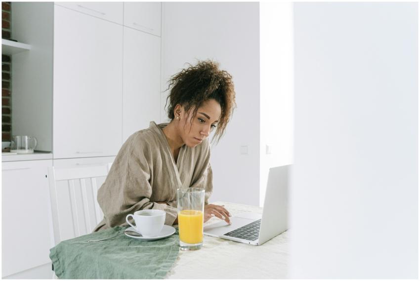 Woman in a bathrobe using a laptop at home, enjoyi