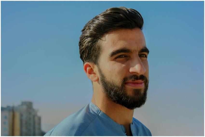 A close-up outdoor portrait of a young man with fa