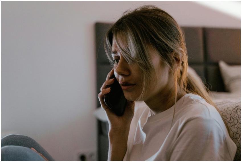 A worried woman on a phone call indoors, conveying