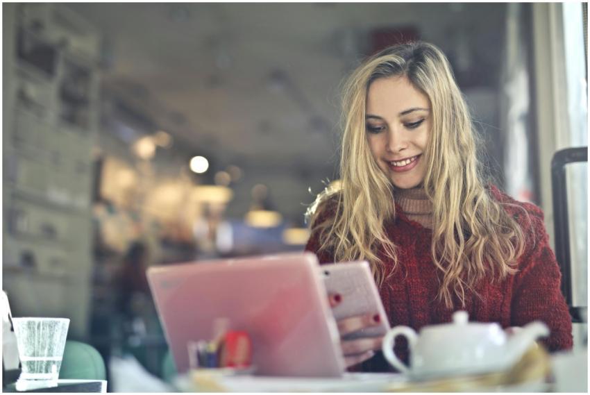 A young woman engaged with a tablet in a warm, inv