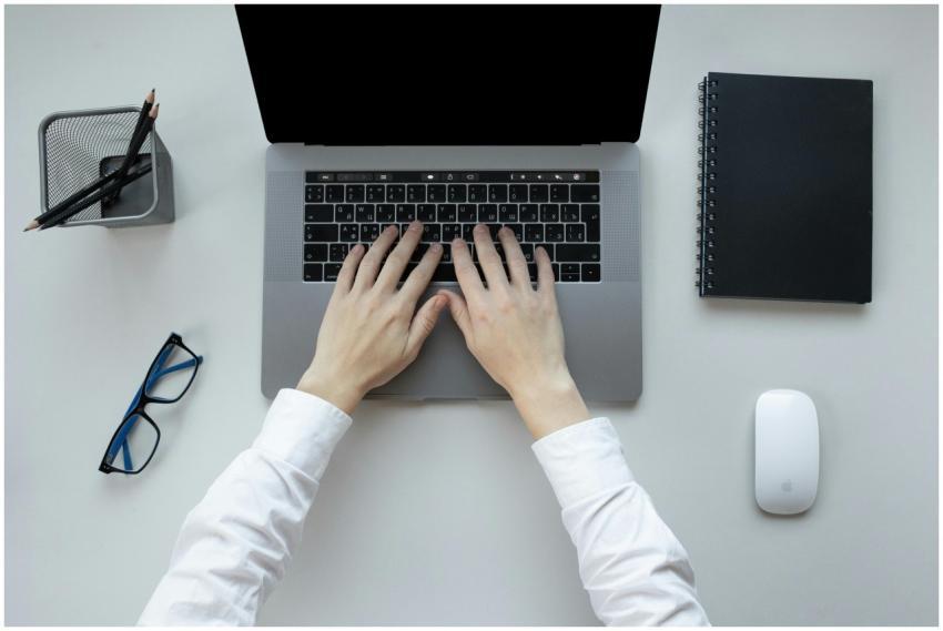 Person typing on a laptop at an office desk with a