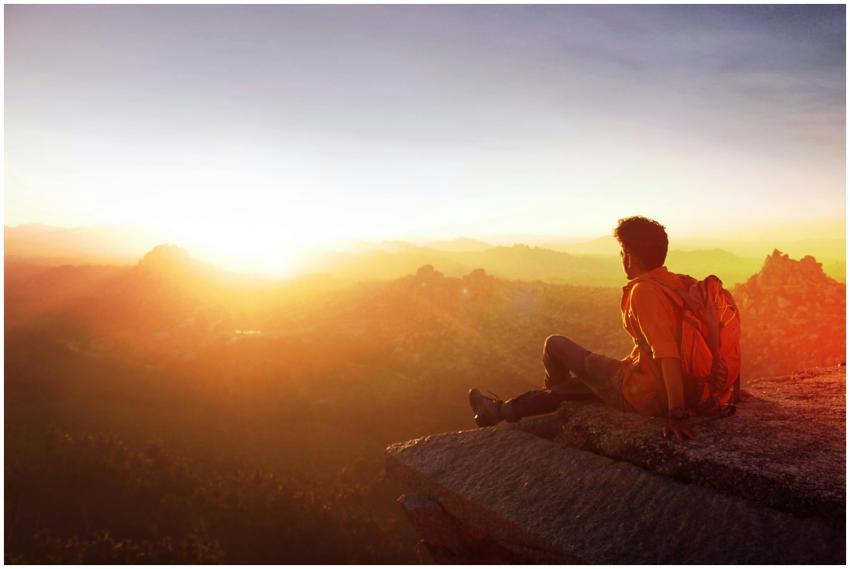 A man enjoys a breathtaking sunset view from a roc