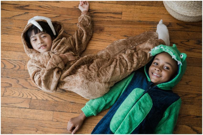 Two smiling children in animal onesies playing tog
