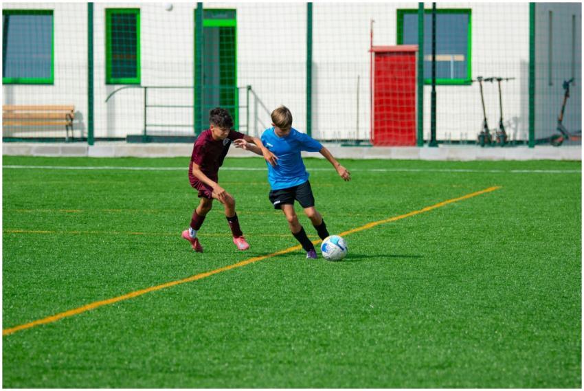 Two young boys playing soccer on an outdoor field